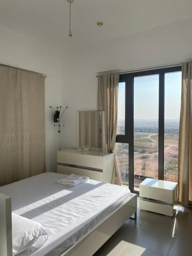 a bedroom with a bed and a large window at Lovely calm 3BR Apt Easy Accessibility to central Dubai with huge balcony and pool view Town Square in Dubai