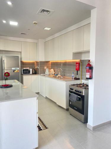 a large kitchen with white cabinets and a stove at Lovely calm 3BR Apt Easy Accessibility to central Dubai with huge balcony and pool view Town Square in Dubai