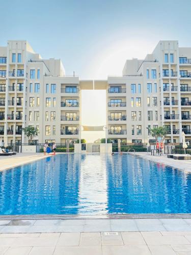 a swimming pool in front of some apartment buildings at Lovely calm 3BR Apt Easy Accessibility to central Dubai with huge balcony and pool view Town Square in Dubai