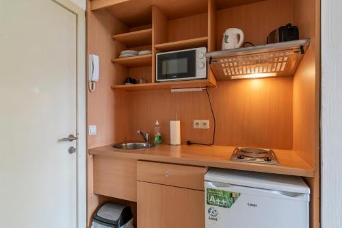 a small kitchen with a sink and a microwave at Condo Gardens Brussels in Brussels