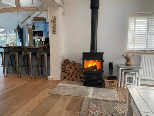 einen Kamin im Wohnzimmer mit Herd in der Unterkunft The Cow Stalls - Stunning Farmhouse with Wonderful Views and Garden - Close to Corfe Castle in Langton Matravers