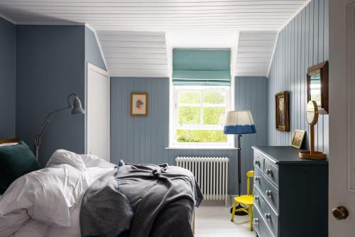 a blue bedroom with a bed and a window at Cuttieshillock in Banchory