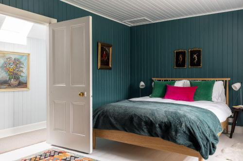 a bedroom with green walls and a bed with a pink pillow at Cuttieshillock in Banchory