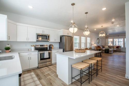 a kitchen with white cabinets and a kitchen island with bar stools at Canyon Escape Luxury Ski home American Fork in American Fork