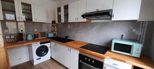 une cuisine avec un micro-ondes et un lave-linge et un sèche-linge dans l'établissement Appartement chaleureux 50m2 hypercentre, à Portbail