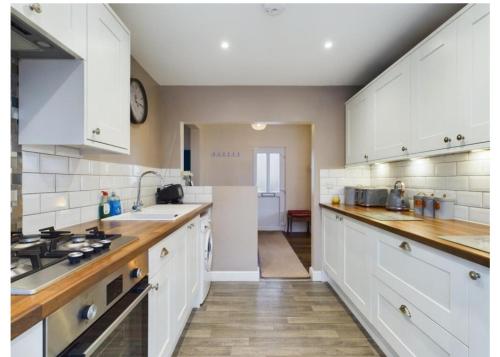 a large kitchen with white cabinets and a sink at Tallets Apartment with Balcony & Parking in Tewkesbury