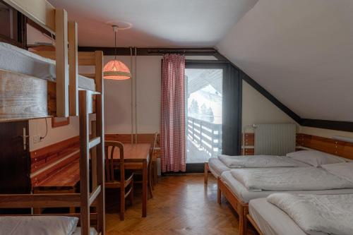 a bedroom with bunk beds and a dining room with a table at Old House - Krvavec ski resort in Cerklje na Gorenjskem