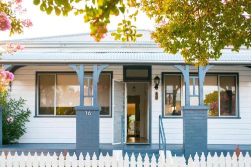 a white house with a fence in front of it at The Sweet Grapevine Cottage in Cessnock