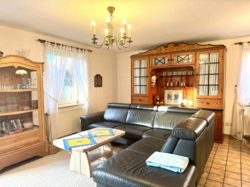 Una sala de estar con un sofá de cuero y una mesa. en Rungholtstrasse Bungalow, en Wyk auf Föhr