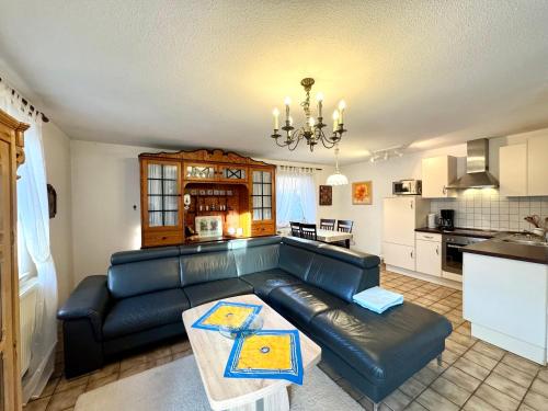 sala de estar con sofá de cuero negro y cocina en Rungholtstrasse Bungalow, en Wyk auf Föhr