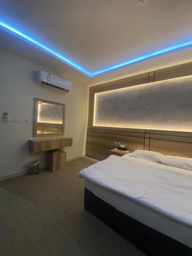 a hotel room with a bed and a blue light at رامة المدينة للشقق المخدومة in Sīdī Ḩamzah