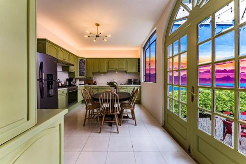 een keuken met groene kasten en een tafel met stoelen bij Roma Elite Residence Spacious and Elegant in Mexico-Stad