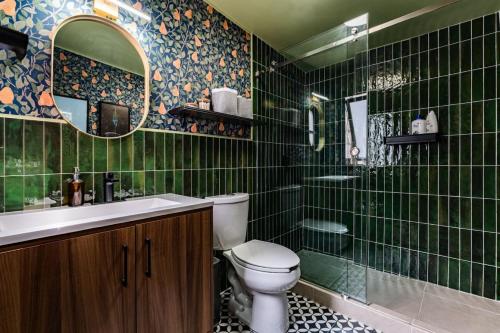 een groen betegelde badkamer met een toilet en een wastafel bij Roma Elite Residence Spacious and Elegant in Mexico-Stad