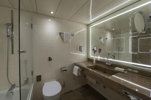 a bathroom with a toilet and a sink and a mirror at Maritim Hotel Bremen in Bremen