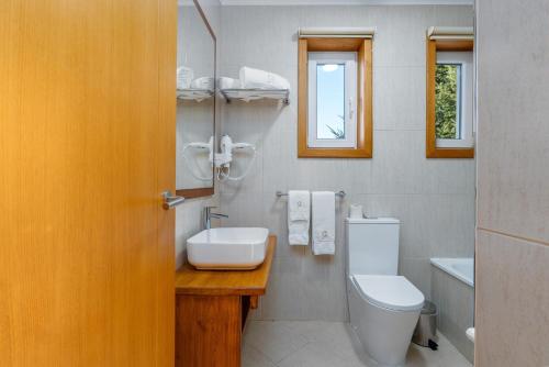 a bathroom with a white toilet and a sink at Casa Avó Chiquinha in Montalegre
