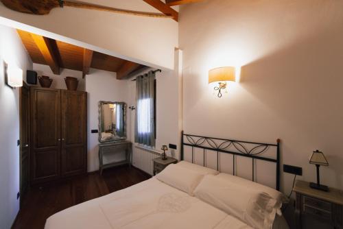 a bedroom with a white bed and a mirror at Ca l'Andreu in Ribera de Montardit