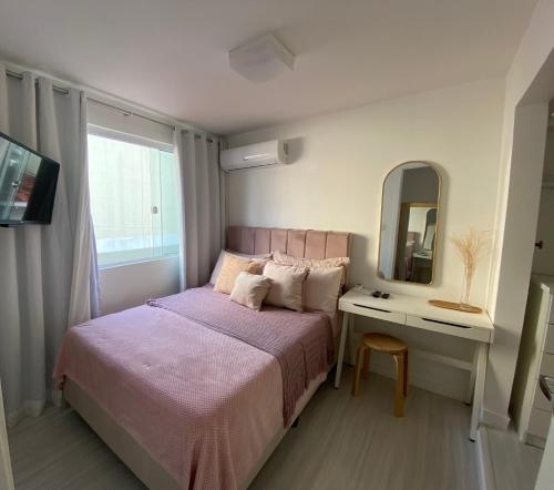 ein kleines Schlafzimmer mit einem Bett und einem Spiegel in der Unterkunft Casa de férias in Balneário Camboriú