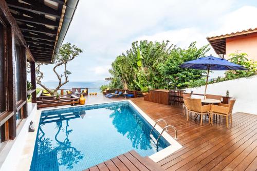 a pool and deck with a table and an umbrella at Maravilha in Búzios
