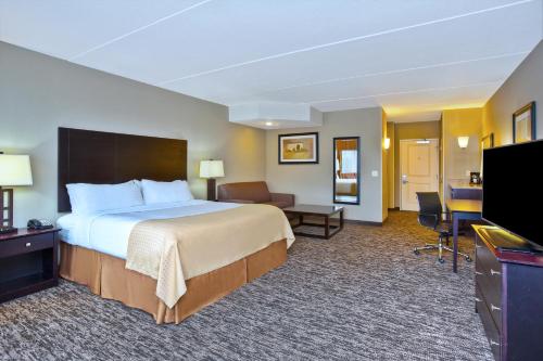 a hotel room with a bed and a flat screen tv at Holiday Inn & Suites Green Bay Stadium, an IHG Hotel in Green Bay