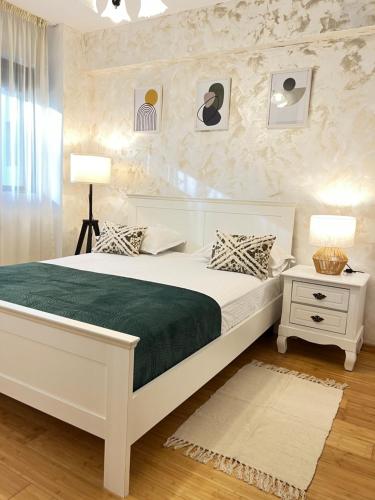 a white bedroom with a bed and a night stand at Apartment near IPJ IASI Copou in Iaşi