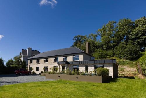 a large white house with a car parked in the driveway at Luxury Eleven Bedroom House Sleeps 23 5-10 mins walk from town Centre in Killarney