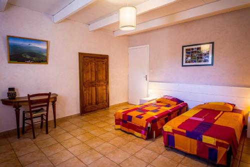two beds in a room with a table and a desk at Gîte Spacieux et Authentique au Coeur de la Nature in Le Poët