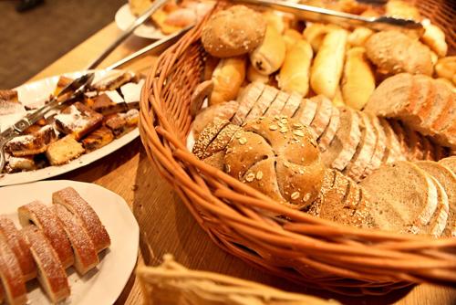 a wooden table with a basket of bread and pastries at Central Hotel Prague in Prague