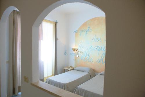 a bedroom with two beds and a mirror at Hotel Corallaro in Santa Teresa Gallura