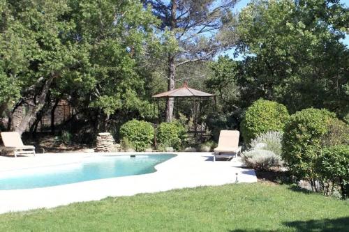 une piscine avec deux chaises et un gazebo dans l'établissement Villa La Raffinée, au coeur des garrigues du Luberon, à Gordes
