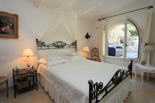 une chambre avec un grand lit blanc et une fenêtre dans l'établissement Villa La Raffinée, au coeur des garrigues du Luberon, à Gordes