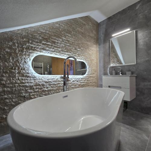 a bath tub in a bathroom with a stone wall at Trebevićki Raj 1 in Brus