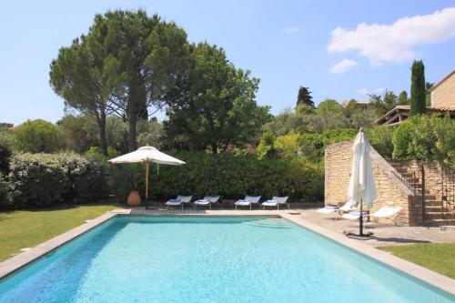 une piscine avec des chaises et un parasol dans l'établissement Villa l'Écrin, piscine et 3 terrasses, à Gordes