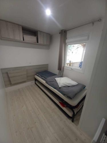 une petite chambre avec un lit et une fenêtre dans l'établissement MH 515 AMIRA TOUT CONFORT 3ch et 2sdb dans camping 4étoiles avec parc aquatique, à Saint-Julien-en-Born