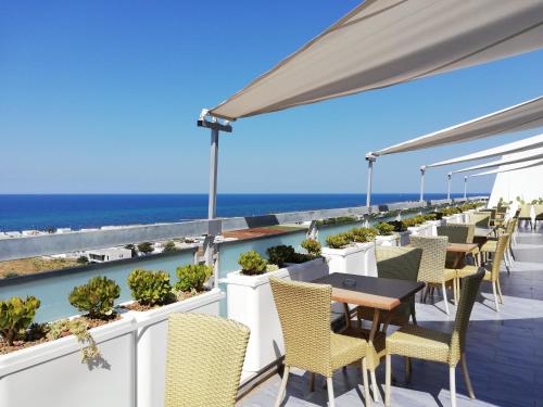 eine Terrasse mit Tischen und Stühlen und Meerblick in der Unterkunft Barion Hotel & Congressi in Bari