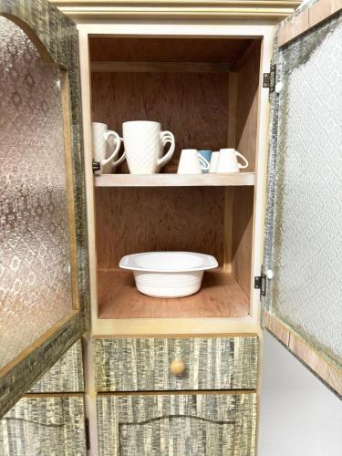 a cupboard with cups and dishes in it at Residence Ville Noire in Mahébourg