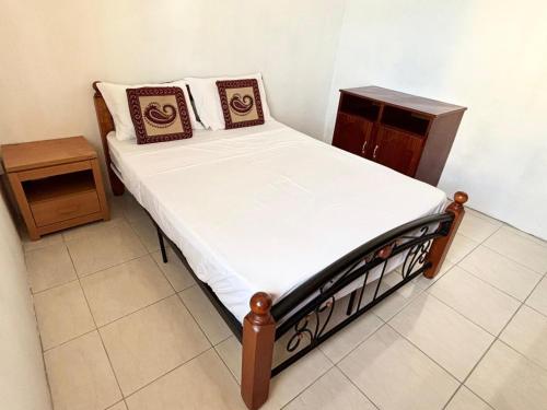 a small bedroom with a bed and a night stand at Residence Ville Noire in Mahébourg