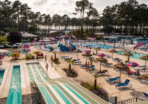 duży basen w parku wodnym z ludźmi w nim w obiekcie MH 515 AMIRA TOUT CONFORT 3ch et 2sdb dans camping 4étoiles avec parc aquatique w mieście Saint-Julien-en-Born