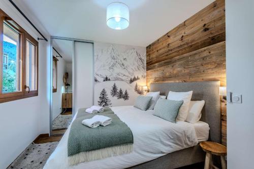 une chambre avec un grand lit avec un mur en bois dans l'établissement Fermes du Planet, à Morzine