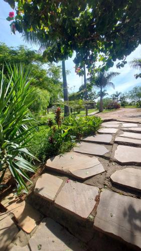 a stone pathway with plants and trees in a park at Pousada Portal da Serra in Carrancas