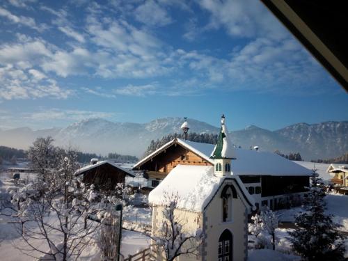 a church covered in snow with mountains in the background at Kapellenblick! geräumiges Apartment in Bad Häring