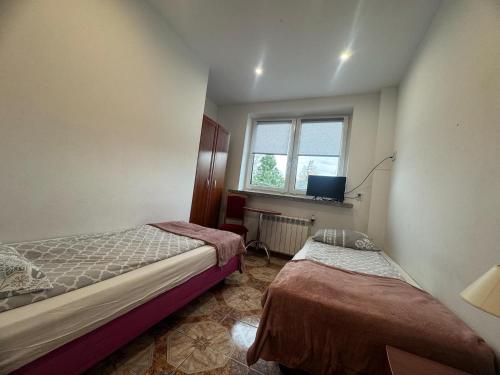 a small bedroom with two beds and a window at OŚRODEK WYPOCZYNKOWY MAZOWSZE W KARPACZ in Karpacz