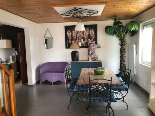 d'une salle à manger avec une table et un canapé violet. dans l'établissement Gîte à 3min de Ste-Mère-Eglise, à Sainte-Mère-Église