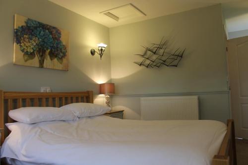 a bedroom with a white bed and a painting on the wall at The Swan Motel, Gillingham in Beccles