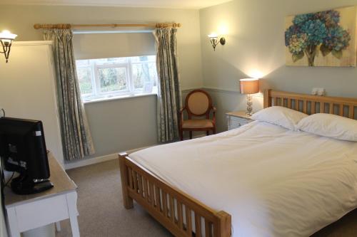 a bedroom with a bed and a desk with a television at The Swan Motel, Gillingham in Beccles