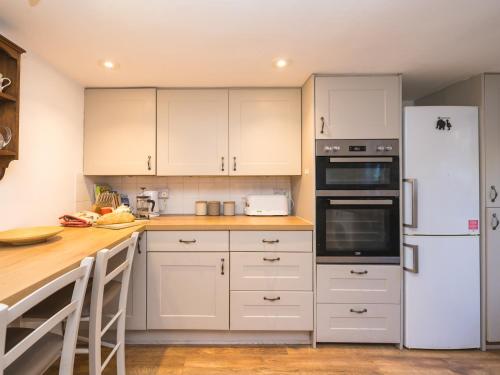 a kitchen with white cabinets and a white refrigerator at Pass the Keys Cosy cottage hideaway set in beautiful countryside in Hopesay