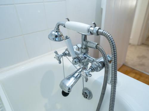 a shower head with a hose attached to a sink at Pass the Keys Cosy cottage hideaway set in beautiful countryside in Hopesay