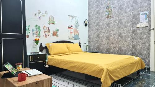a bedroom with a bed with a yellow bedspread at Minh Trang Villa Hoi An -BBQ Garden in Hoi An
