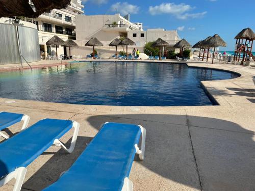 a swimming pool with blue chairs and umbrellas at a resort at Condominio Privado Villas Marlin Zona Hotelera Cancun in Cancún