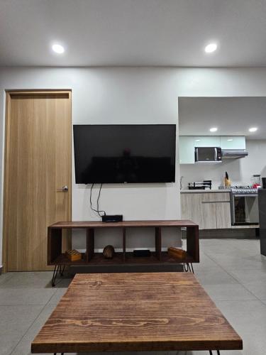 een woonkamer met een tafel en een tv aan de muur bij NSI Alameda Park Humboldt Mexico City in Mexico-Stad