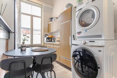 a kitchen with a washing machine and a table at Beautiful Serenity Stylish Shared Apt at Ghent's Central in Ghent
